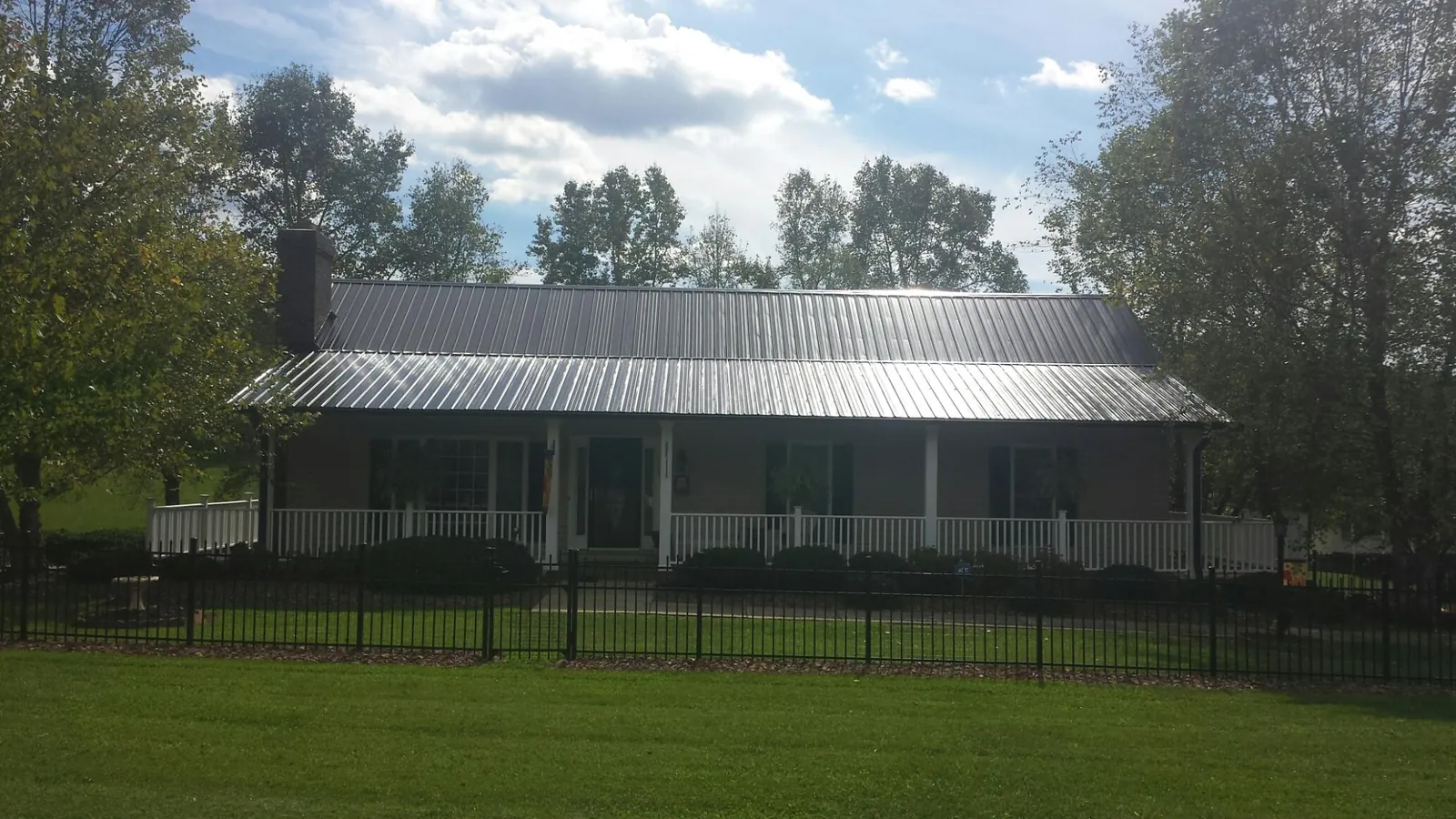 Gray metal roof on a brick ranch with a full width front porch — Gutter Guard Installation work by our crew in Frankfort